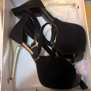 Black suede peep toe stiletto. Straps cross across the front. Brand new in box